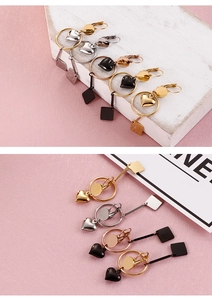 Detail of minimalist titanium steel heart and square earrings in gold, silver and black