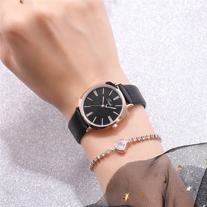 Detail of slim leather strap quartz watch with sparkling heart bracelet set on woman's wrist
