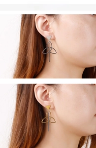 Model wearing elegant long geometric triangle drop earrings in polished gold and silver