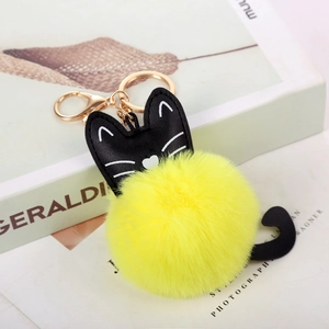 Dettaglio portachiavi a gatto con pompon giallo in pelliccia sintetica e pelle nera lucida