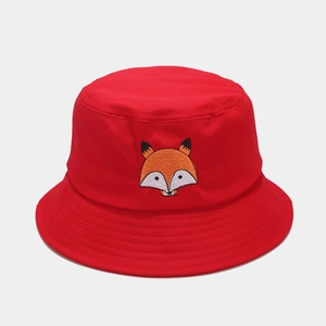Détail d'une broderie de renard sur un chapeau bob en coton rouge avec coutures renforcées