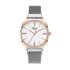 Détail du boîtier en or rose avec bracelet en maille argentée et cristaux sur montre quartz