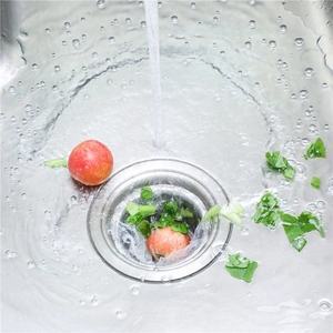 Close-up of a white mesh sink strainer bag filtering food scraps in a stainless steel sink