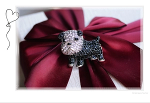 Macro detail of dog brooch featuring sparkling black and white crystals on red satin box