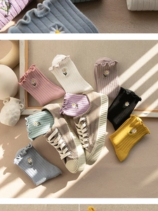 Detail showing ruffled cuffs and daisy embroidery on various pastel knit socks