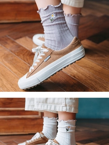 Detail of light purple floral embroidered cotton socks with ruffle cuff on wooden floor