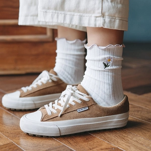 Classic camel suede low-top sneakers with white laces on warm wooden flooring