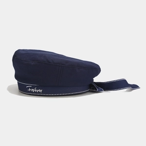 Detail of navy blue beret featuring Forever embroidery and ribbon bow with white stitching