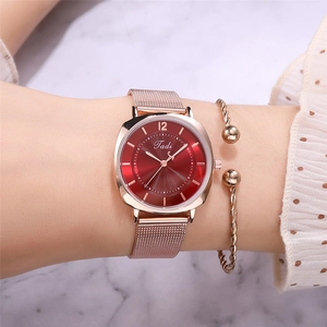 Gros plan d'une montre en maille or rose et d'un bracelet torsadé sur un poignet