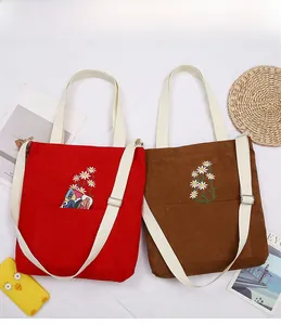 Detail of red and brown corduroy tote bags with daisy embroidery and adjustable straps