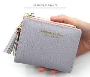 Détail d'un portefeuille gris pour femme avec texture Saffiano et fermeture à pompon