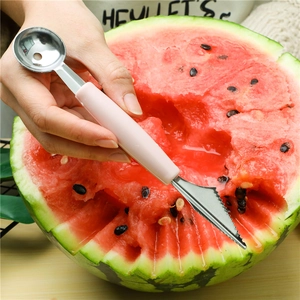 Dual-head stainless steel fruit baller with pink handle carving a fresh watermelon