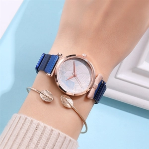 Close-up of rose gold watch with leaf bracelet on wrist against elegant background