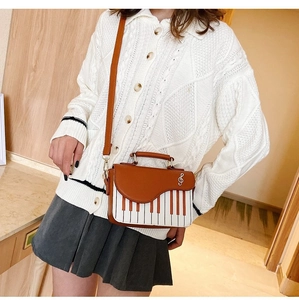 Detail of creative piano-themed crossbody bag with keyboard pattern and music note charm