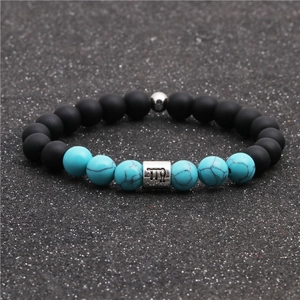Detail of Virgo zodiac charm on black matte beads and turquoise beaded bracelet