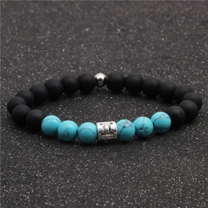 Detailed macro view of Gemini zodiac charm on black matte and turquoise beaded bracelet