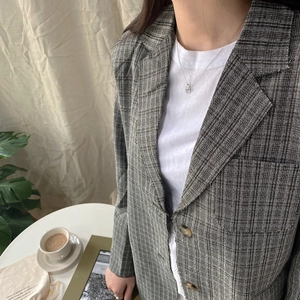 Collana a catena d'argento minimalista abbinata a un blazer grigio a quadri per un look chic