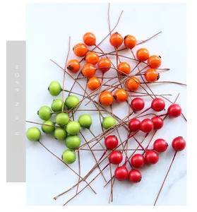 Detailed view of glossy red, orange, and green artificial berries for DIY floral crafts