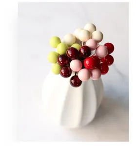 Detailed view of colorful 10mm artificial berries in a white striped ceramic vase