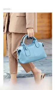 Close-up of light blue litchi pattern leather handbag with golden hardware and stitching