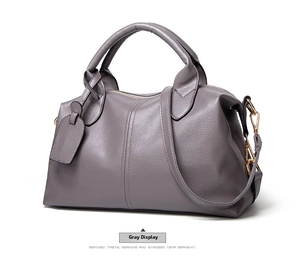 Detail view of the pebbled leather texture and adjustable strap on a gray Boston bag