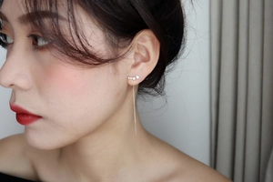 Macro detail of elegant silver star drop earrings worn by a model in a minimalist style