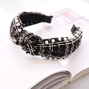 Detail view of a black and white tweed knot headband with elegant pearl embellishments