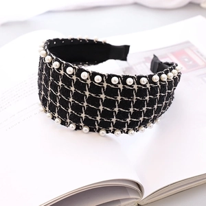 Detail of tweed headband with pearl trim showing woven texture on a white book