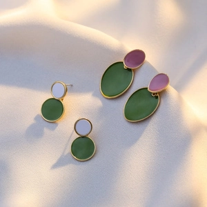 Macro detail of geometric enamel earrings with olive green and lilac gold-plated frames