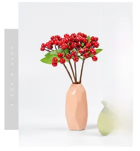 Close-up of artificial red berry branches in a geometric pink vase for home decor