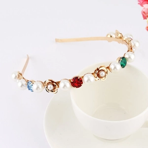 Detailed close-up of golden metal headband with pearls, colorful gems and roses on white cup