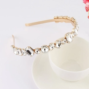 Macro shot of gold floral headband with rhinestones and crystals leaning on a white cup