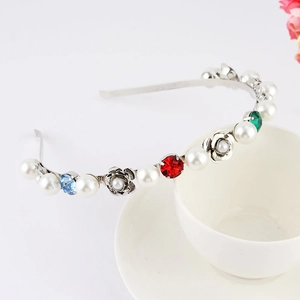 Macro shot of silver floral headband with colorful rhinestones and faux pearls on a cup