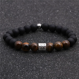 Detail of beaded bracelet with tiger eye stones and matte black onyx featuring Gemini charm