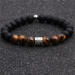 Detailed shot of tiger eye and matte black beads bracelet with silver Pisces zodiac charm