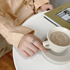 Detailed view of layered silver geometric open ring worn on finger in elegant setting