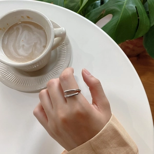 Detail shot of a minimalist double-layered silver ring worn in a lifestyle coffee setting