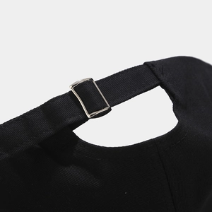 Detalle de gorra de béisbol de algodón negro con hebilla de metal plateada ajustable en la parte trasera