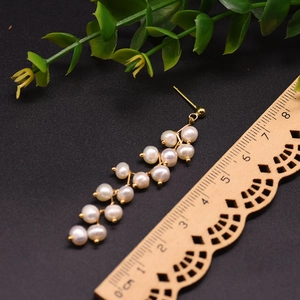 Long natural freshwater pearl drop earrings with 18k gold plating on black background