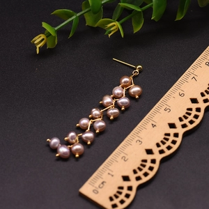 Detail view of 6.5cm long mauve pearl cluster earrings with 18k gold plated wire weaving