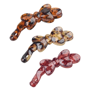 Three bow-shaped resin banana hair clips in tortoise shell and plaid patterns