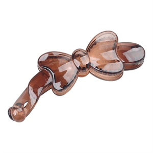 Macro detail of brown transparent resin bow-shaped banana hair clip on white background