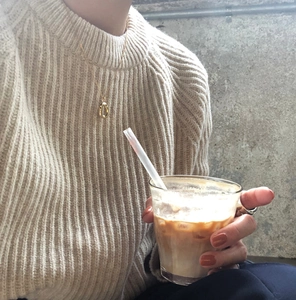 Detail of a minimalist gold oval pendant necklace worn with a cozy casual sweater