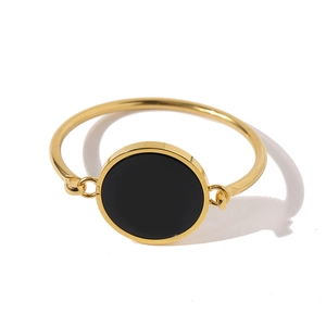 Detail of a gold-plated bangle featuring a circular black onyx inlay on white background