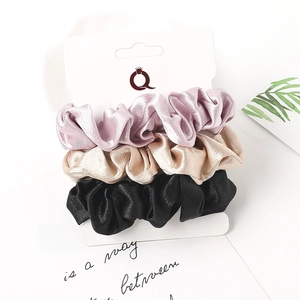 Three-piece set of satin hair scrunchies in purple, gold, and black silk textures
