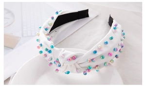 Detail of white fabric headband featuring a top knot and colorful pearl embellishments