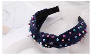 Detail of dark blue knotted headband decorated with colorful pearls on satin fabric