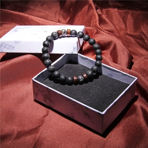 Close-up of men's volcanic stone bracelet with wooden beads in a marble gift box