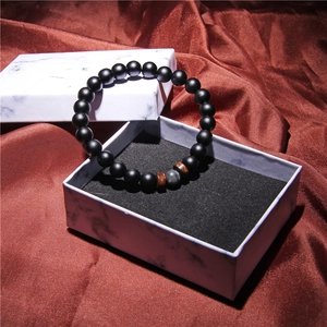 Close-up of black matte beads and tiger eye stone bracelet on red silk fabric