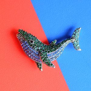 Antique silver whale brooch with sparkling green and blue crystals in a jumping pose